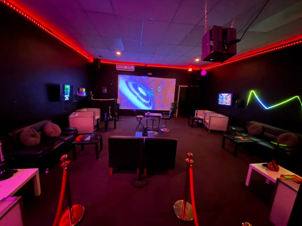 The main room at Saan Gaming Lounge — leather seating under red neon light.
